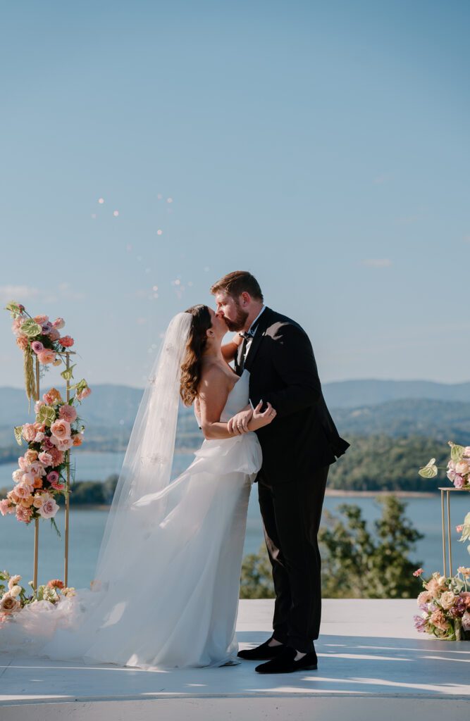 Bride and groom first kiss at ceremony with fire work surprise for the bride at colorful summer backyard wedding.