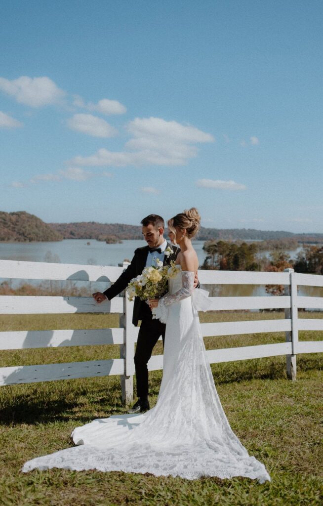 Couple pose alongside white fence at water front venue, Whitestone Inn. This east Tennessee wedding venue  is full of southern charm and vintage touches.