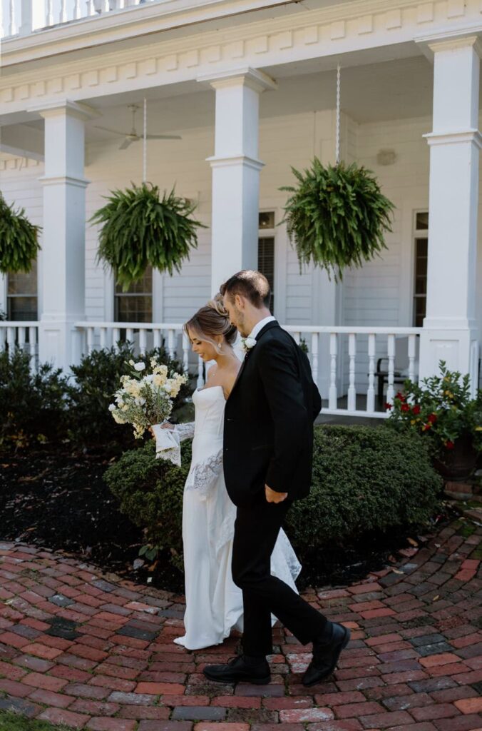 Couple walks along brick path outside The Manor House located on the property at Whitestone Inn, an east Tennessee wedding venue.