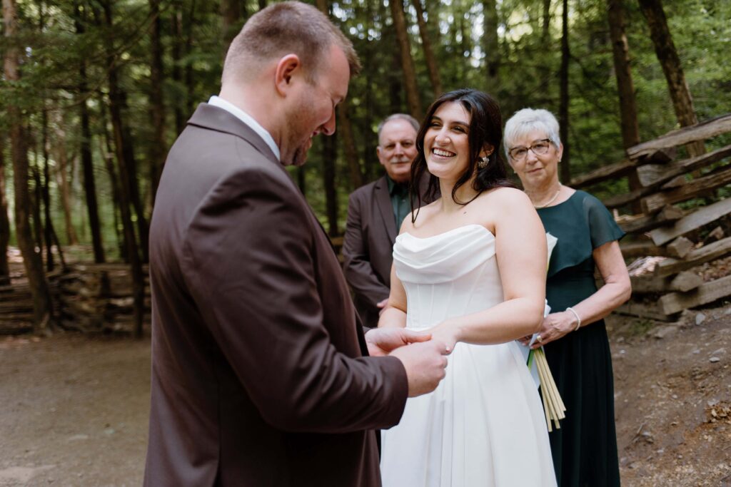 Couple smile at each other as they exchange rings during their summer elopement in the Smoky Mountain National Park.