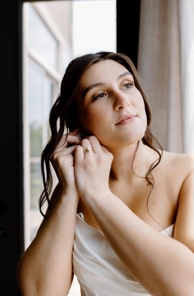 Documentary inspired elopement photographer captures bride putting in her earrings as she gets ready for her wedding day.