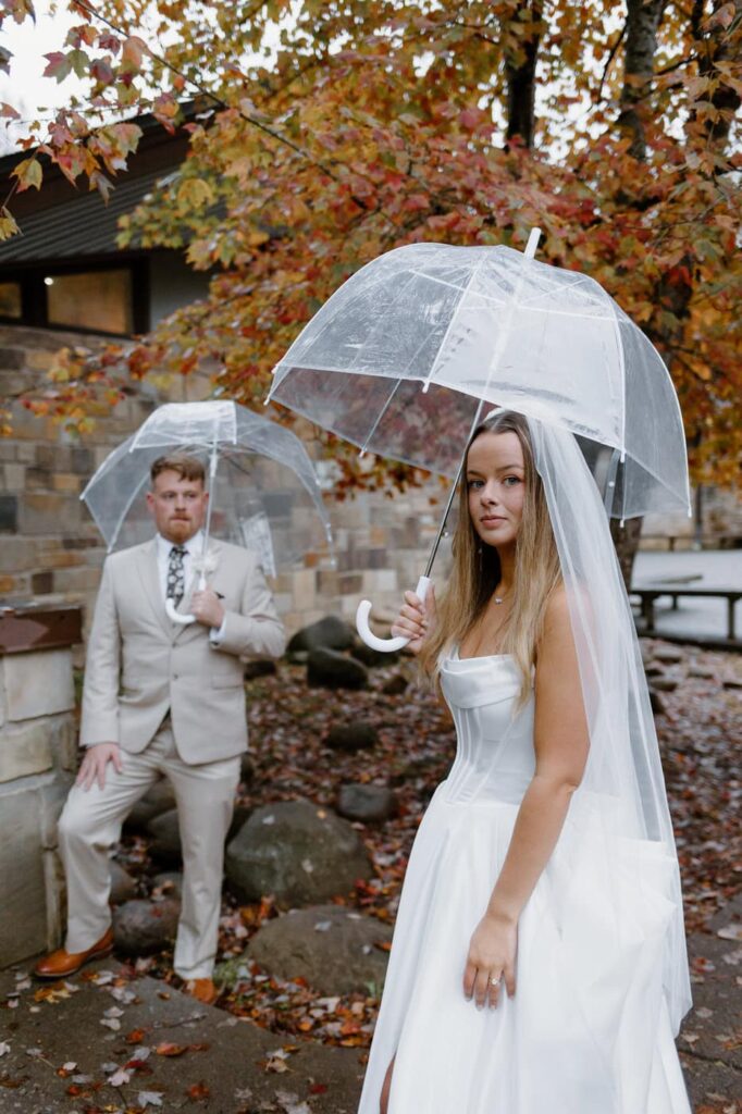 Couple poses together with clear umbrellas during their couples portraits for a Great Smoky Mountain elopement.