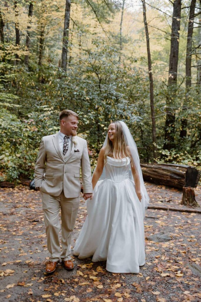 Couple walks hand in hand down a wooded trial during their couple's portrait for their Great Smoky Mountain elopement.