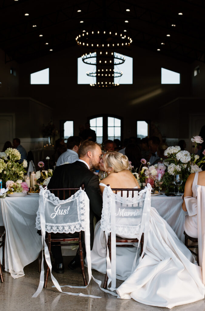 Bride and groom kiss at head table during reception at Tennessee wedding venue, The Loyston.