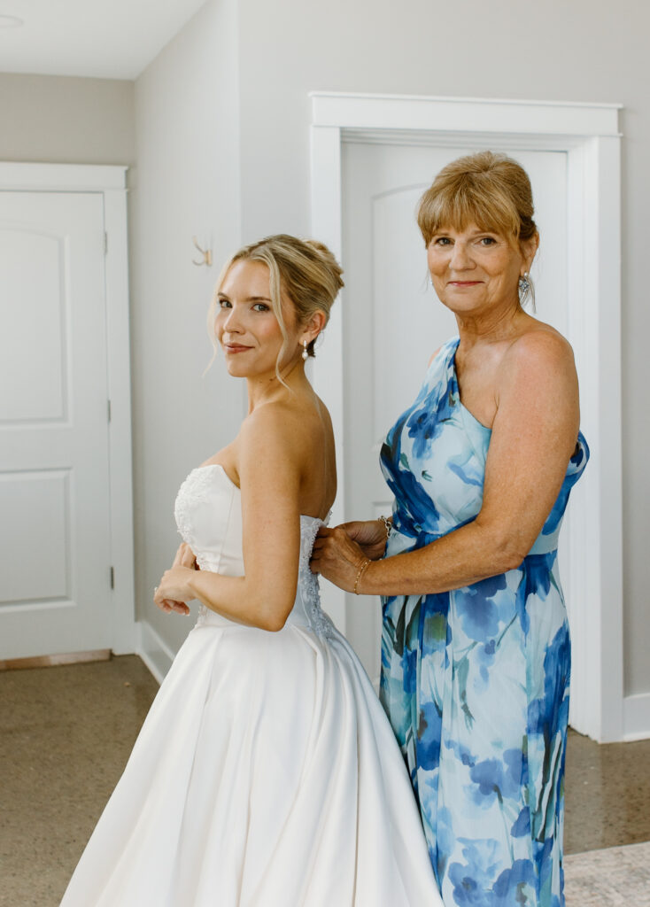 Mother of the bride helping the bride into her dress for getting ready photos at The Loyston wedding venue.