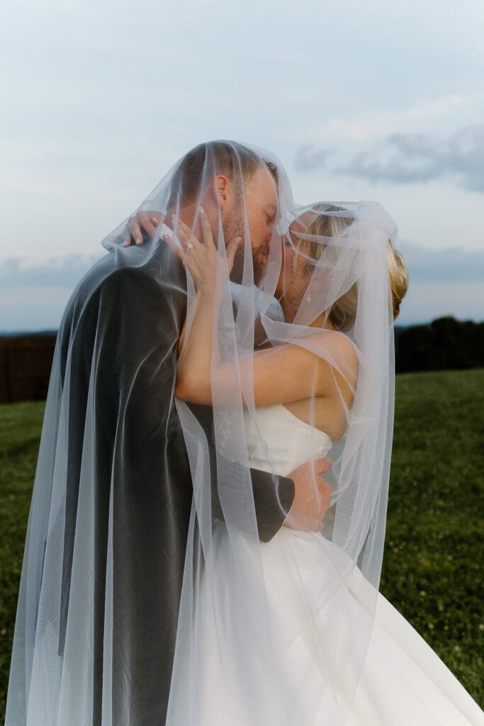 Bride and groom kissing under the veil at the Loyston wedding venue in Tennessee.