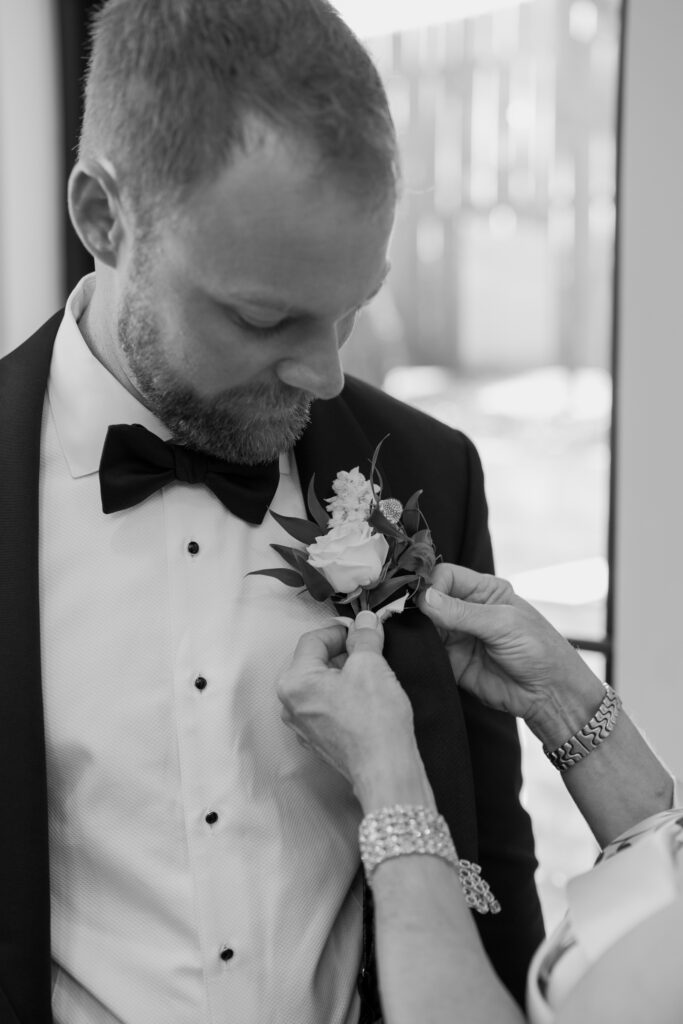 Mother of the groom assists groom with getting ready at the Loyston wedding venue.