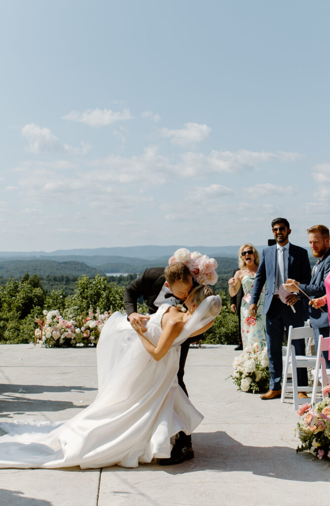 Bride and groom dip kiss in the aisle at The Loyston Wedding Venue.