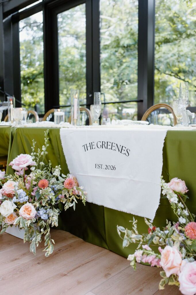 Reception table with olive green and colorful pastel florals at Nichols Heir wedding venue, The Glass House.