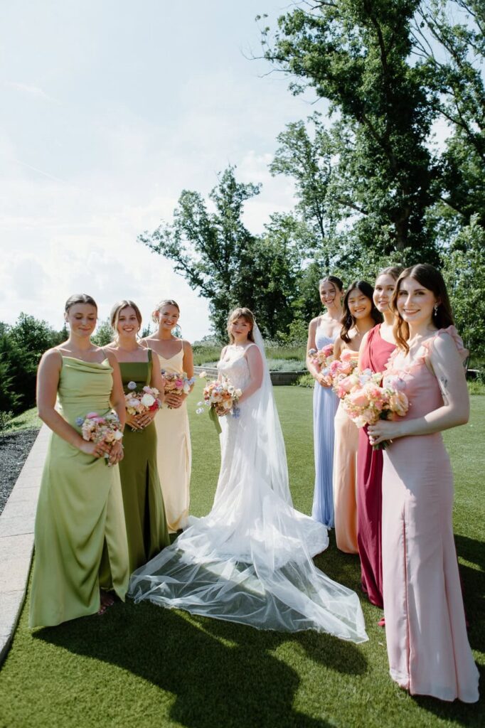 Bridal party portrait of bride and her bridesmaids in colorful pastel dresses.