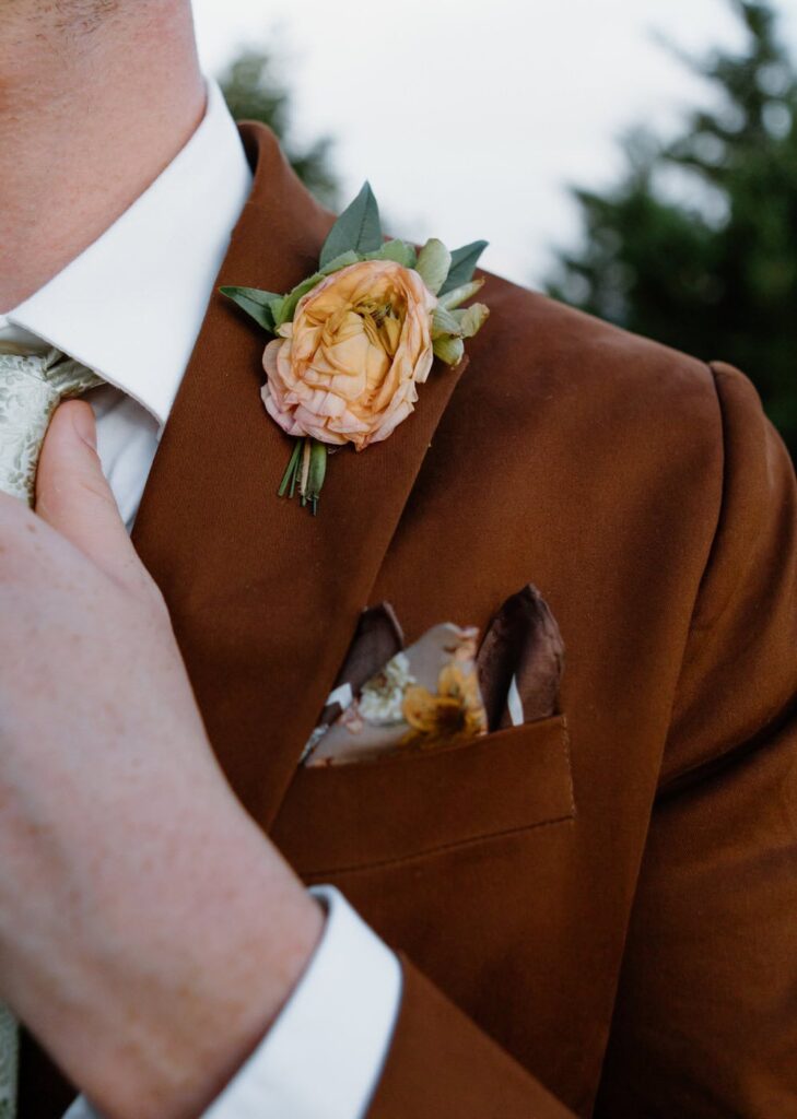 Brown groom's suit with pastel orange boutonniere.