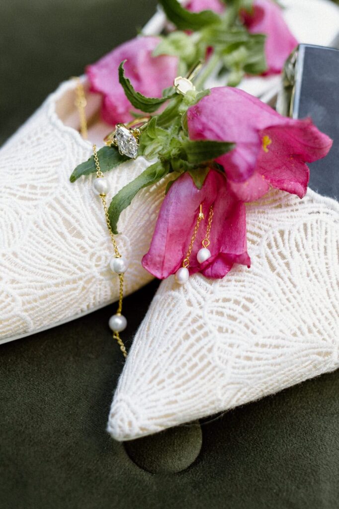 White lace bridal shoes, kite cut diamond ring, and purple florals captured for wedding day detail photos.
