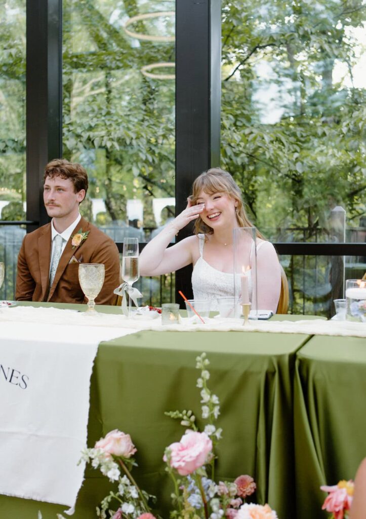Candid emotional photo of bride laughing with tears of joy during the maid of honor speech. 
