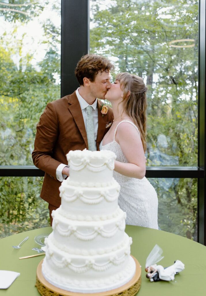 Bride and groom kiss as the cut their wedding cake together at Nichols Heir Wedding venue.