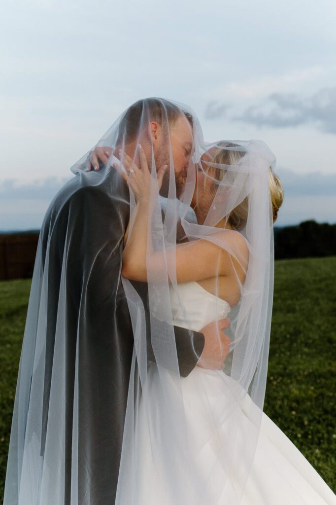 Bride and groom kissing under the veil at the Loyston wedding venue in Tennessee.