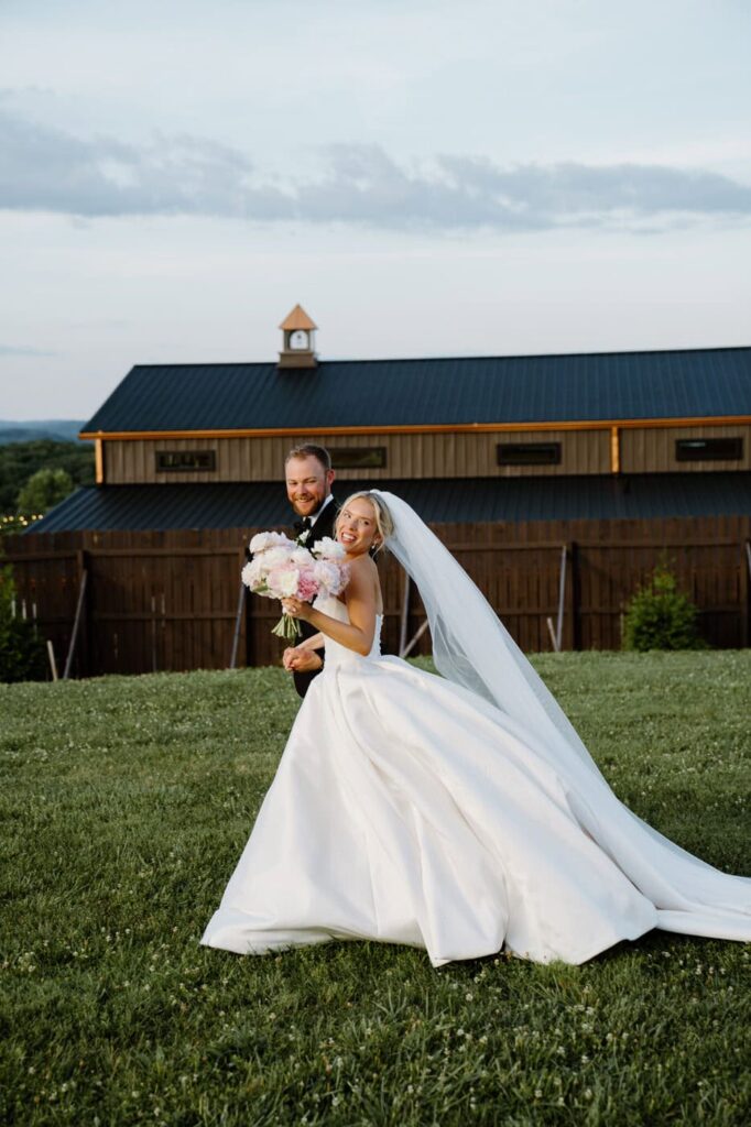 Bride and groom playfully run through the grass at hillside wedding venue, The Loyston in Tennessee.