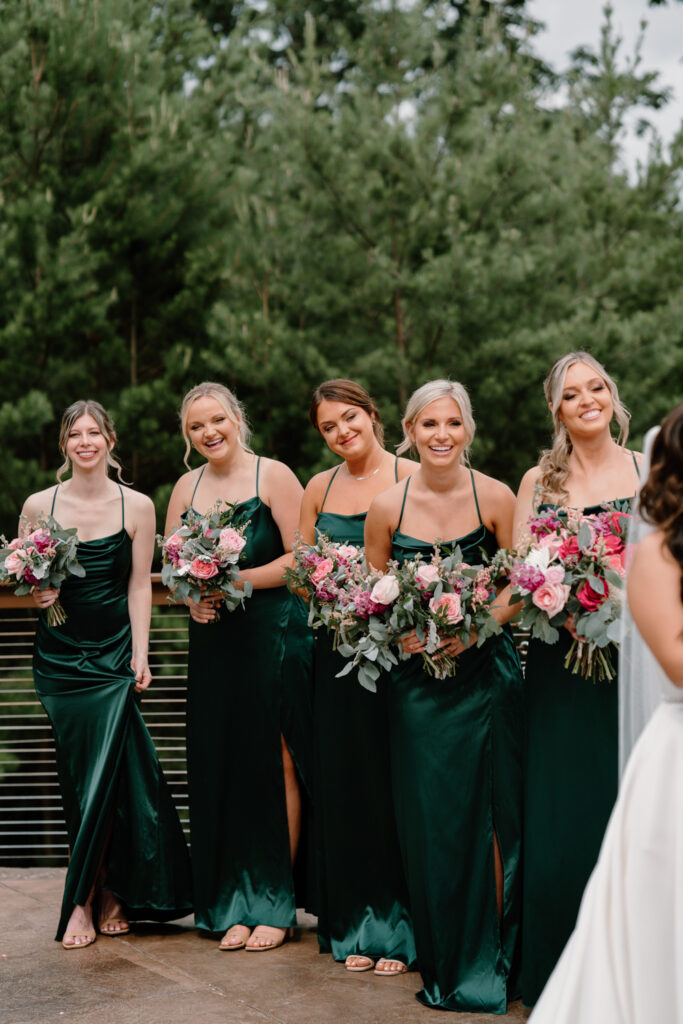 Emerald green bridesmaids dresses paired with color summer bouquet.